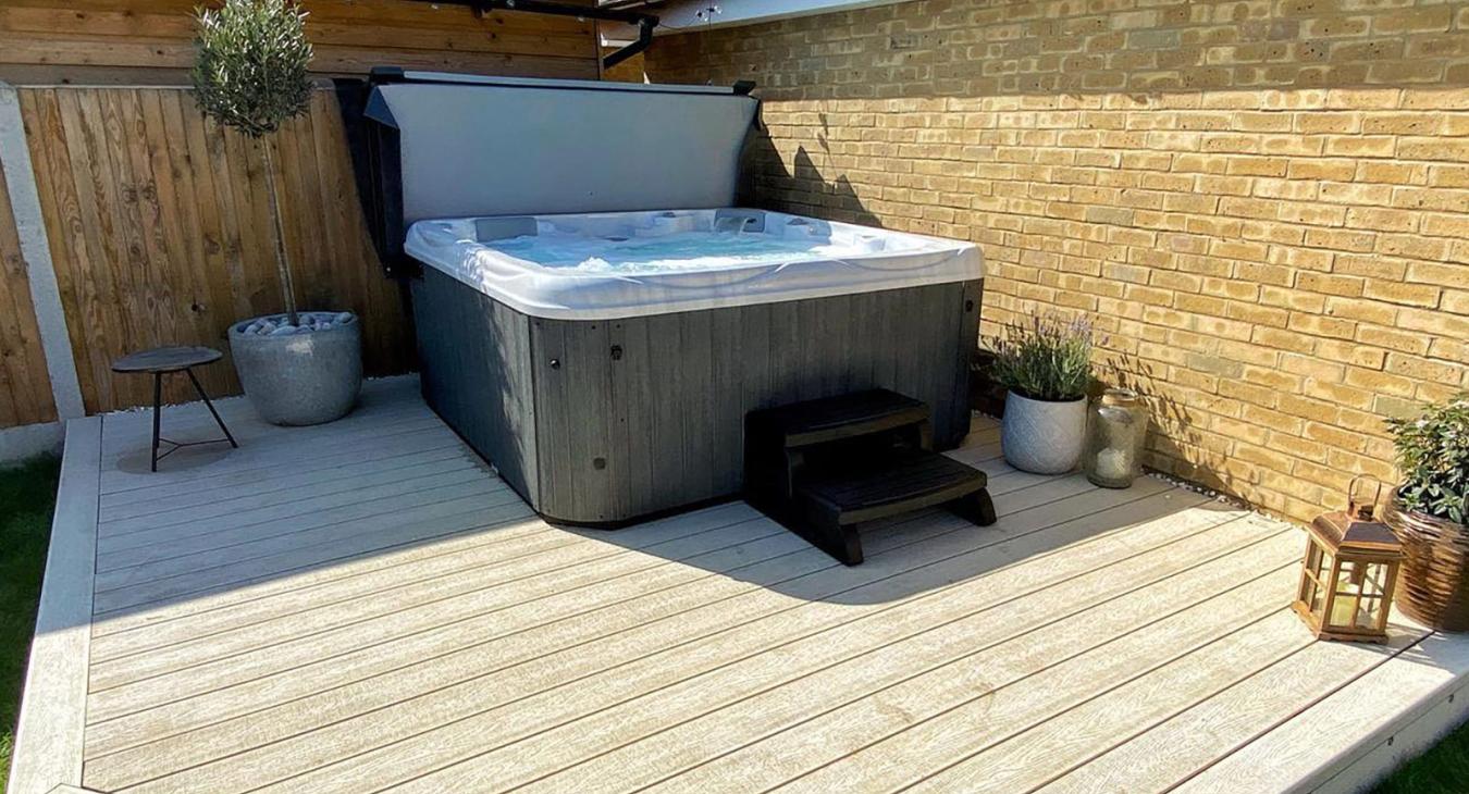 Hot tub installed on a private deck with outdoor seating and scenic hillside views.